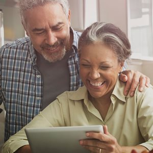 STOCK IMAGE of a smiling senior couple looking at a tablet computer